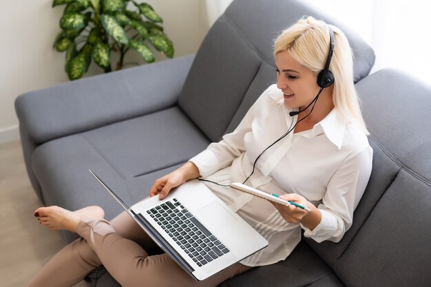 Bella studentessa sorridente che utilizza il servizio di formazione online. Giovane donna che guarda nel display del computer portatile guardando il corso di formazione e ascoltandolo con le cuffie. Moderno concetto di tecnologia di studio