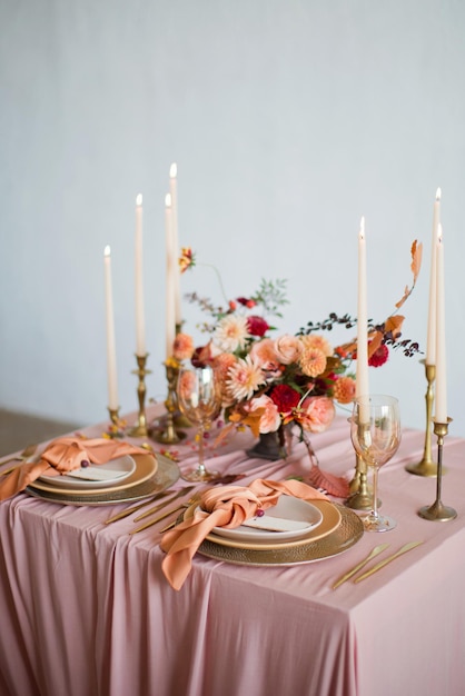 Bella tavola con fiori autunnali tovaglioli arancioni e rosa e candele accese Concetto di matrimonio autunnale