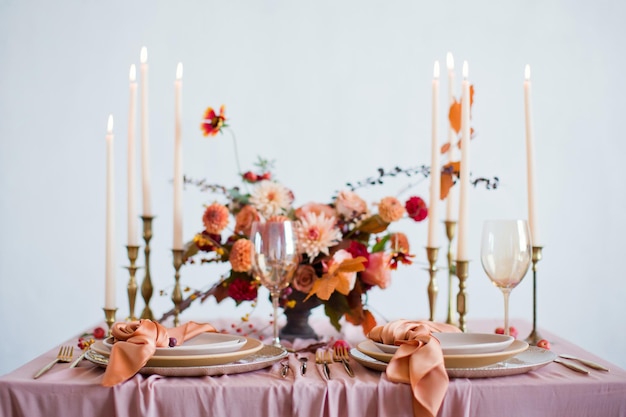 Bella tavola con fiori autunnali tovaglioli arancioni e rosa e candele accese Concetto di matrimonio autunnale