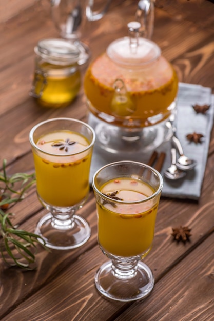 Bella teiera in vetro con tè all'olivello spinoso arancione.