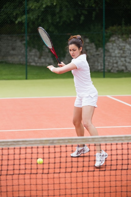 Bella tennista che colpisce palla