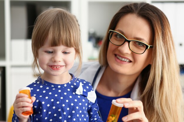 Bella tenuta femminile sorridente di medico nella pillola delle armi