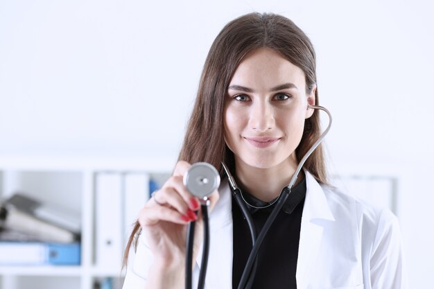 Bella testa femminile sorridente dello stetoscopio della stretta femminile del medico