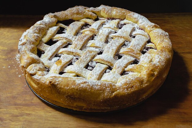 Bella torta di ciliegie rotonda con il primo piano superiore della grata della pasta su una tavola di legno