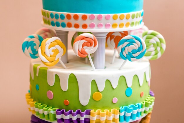 Bella torta multicolore per bambini da più strati decorata con dolci.