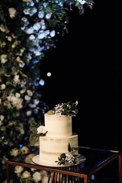 Bella torta nuziale con fiori e un grande arco nuziale