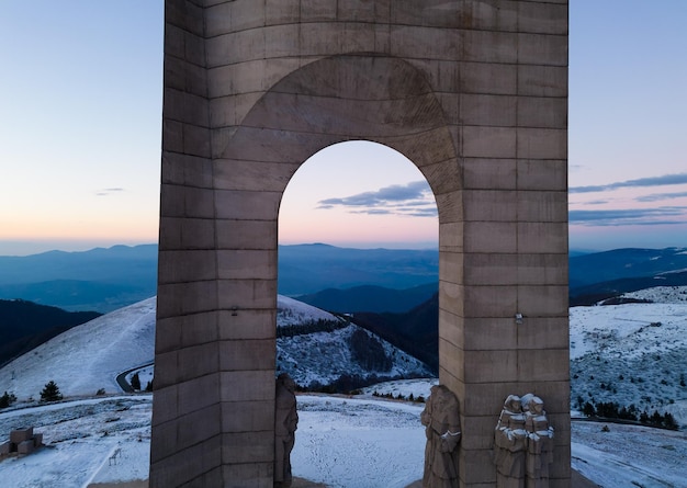 Bella vista aerea delle montagne innevate e del Monumento Arco della Libertà sulla cresta principale dei Monti Balcani Bulgaria nella mattinata invernale