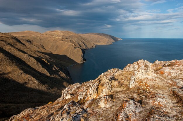 Bella vista dalle alte scogliere al Lago Baikal. Il Sole splende. Nuvole nel cielo.