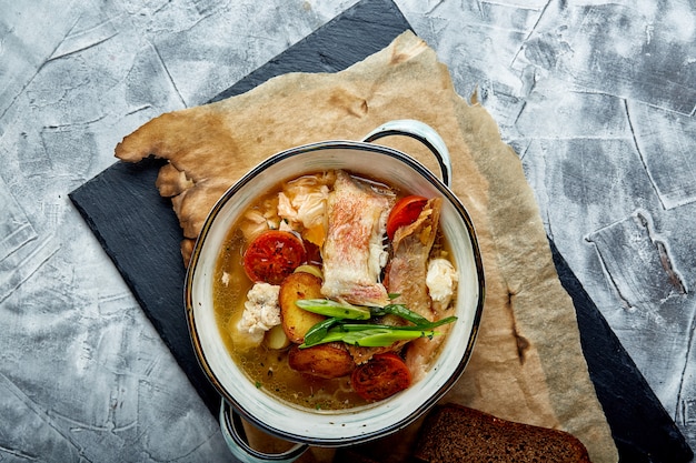 Bella vista della zuppa di pesce in un piatto bianco, su uno sfondo di pietra