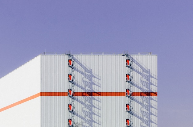 Bella vista di un edificio bianco con una linea arancione che lo attraversa e una scala sul tetto