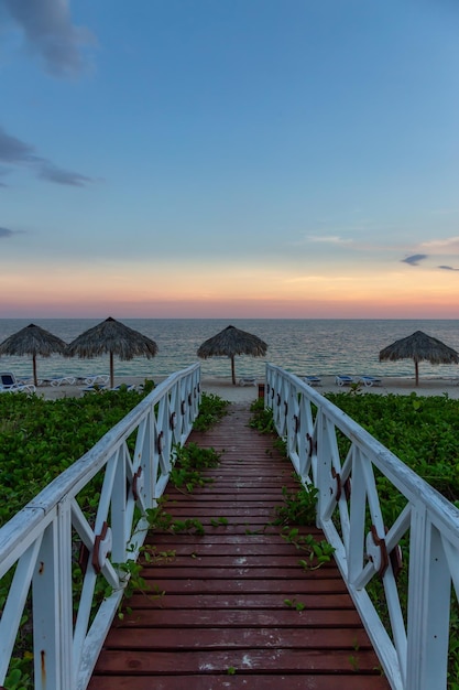 Bella vista di un sentiero in legno che conduce alla spiaggia sabbiosa sul Mar dei Caraibi a Cuba