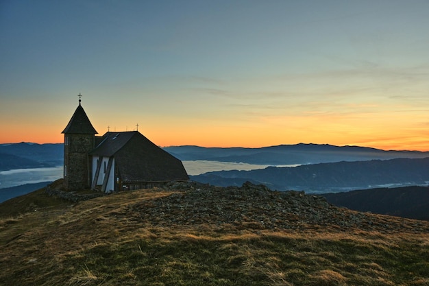 Bella vista di una vecchia chiesa su una collina in montagna al tramonto