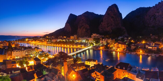 Bella vista panoramica aerea del fiume Cetina, delle montagne e della città vecchia di notte, Omis, località turistica molto popolare in Croazia