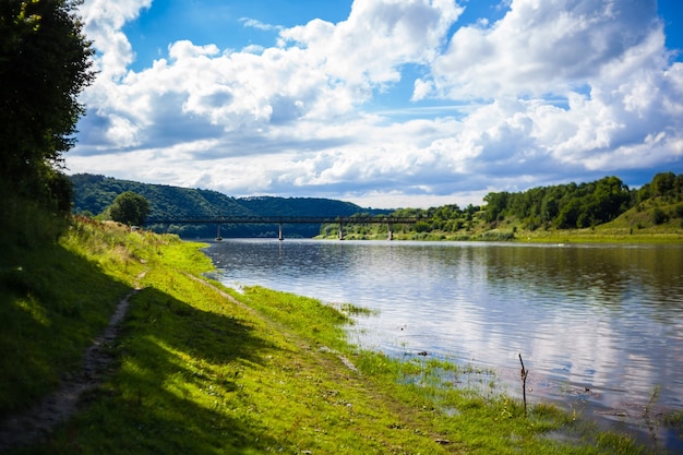 Bella vista sul fiume Dniester e la sua sponda in una soleggiata giornata estiva con sfondo di ponte contro le colline. Ricreazione all'aperto. Nuoto, vacanze estive, attività all'aperto.