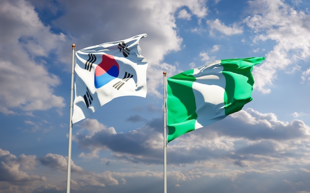 Belle bandiere di stato nazionali della Corea del Sud e della Nigeria insieme sul cielo blu