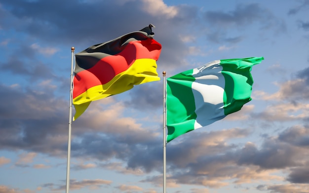 Belle bandiere di stato nazionali della Germania e della Nigeria insieme sul cielo blu