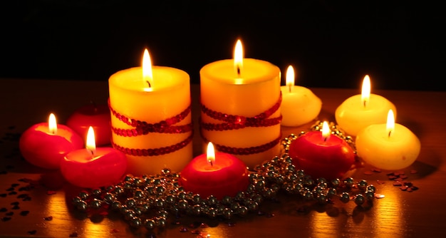 Belle candele e decorazioni su tavola di legno su sfondo nero