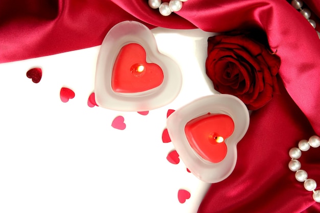 Belle candele e rose su sfondo di seta rossa