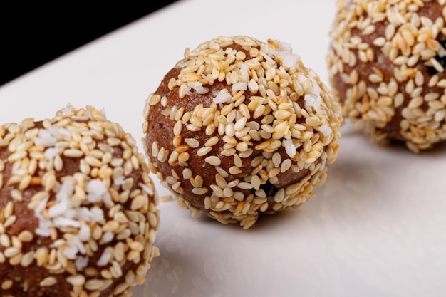 Belle caramelle con semi di sesamo su un piatto bianco su sfondo nero