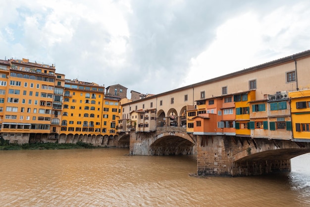 Belle case gialle colorate su uno storico ponte d'epoca con un fiume a Firenze in Italia