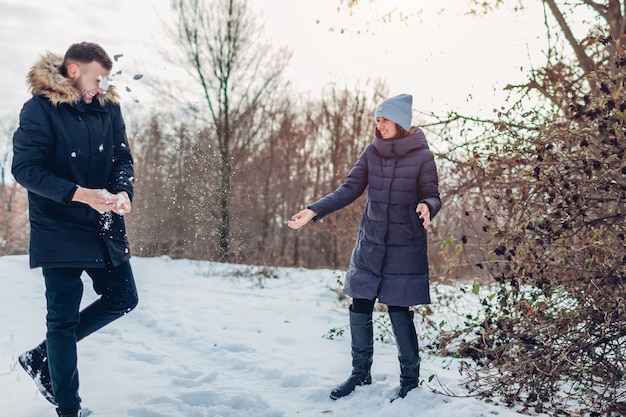 Belle coppie amorose che giocano insieme le palle di neve nella foresta di inverno. Le persone si divertono all'aperto