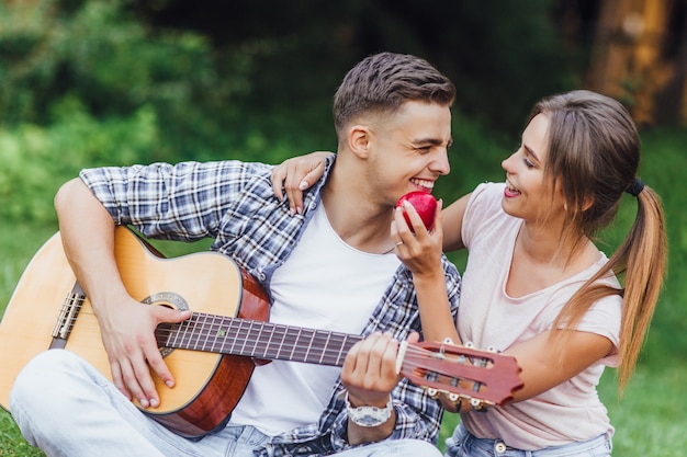 Belle coppie castane che godono del tempo di picnic all&#39;aperto, sono playin alla chitarra