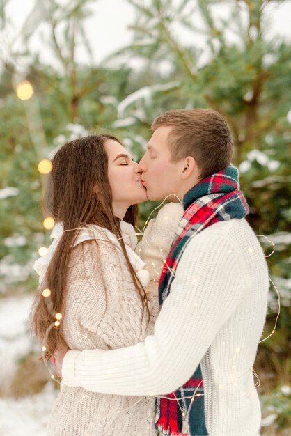 Belle coppie che baciano nella foresta nevosa