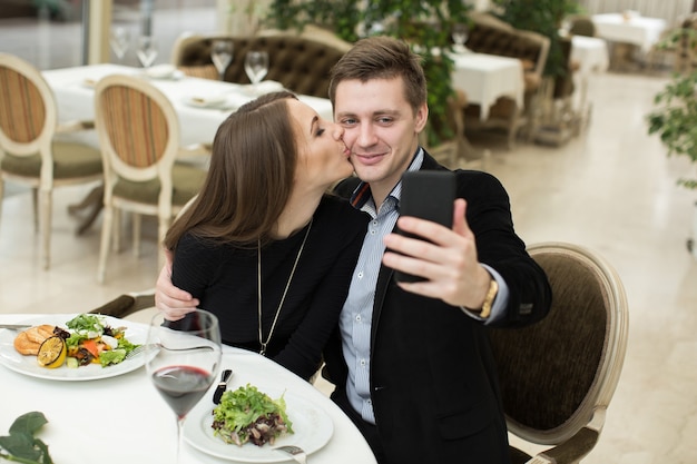 Belle coppie che prendono la foto del selfie in un ristorante