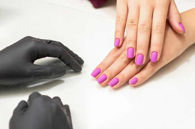 Belle dita con unghie viola dopo la procedura di smalto nel salone di manicure.