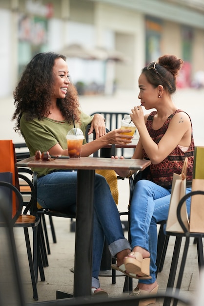 Belle donne alla moda che condividono dolci e deliziosi cocktail quando si incontrano al bar all'aperto