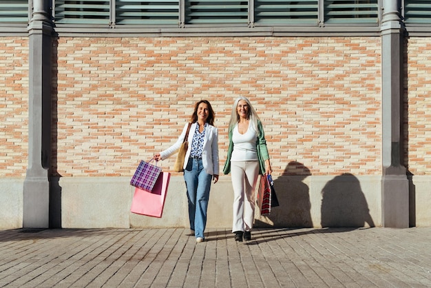 Belle donne anziane che si legano all'aperto in città Attraenti amiche mature e allegre che si divertono a fare shopping e a legare concetti sullo stile di vita degli anziani