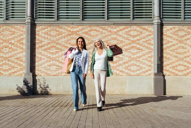 Belle donne anziane che si legano all'aperto in città Attraenti amiche mature e allegre che si divertono a fare shopping e a legare concetti sullo stile di vita degli anziani