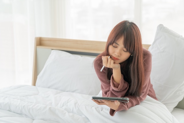 belle donne asiatiche che lavorano con tablet sul letto