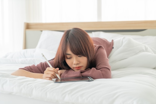 belle donne asiatiche che lavorano con tablet sul letto