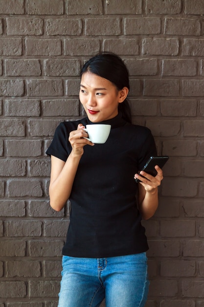 Belle donne asiatiche che sorridono con la tazza di caffè.