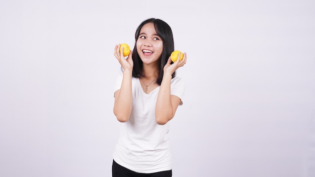 Belle donne asiatiche con un limone isolato sulla superficie bianca