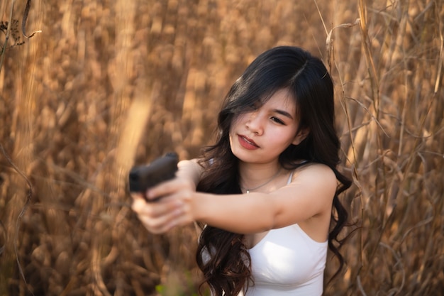 Belle donne asiatiche puntano la pistola sull'erba secca