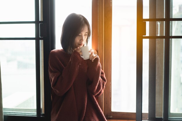 Belle donne che bevono caffè caldo accanto alla finestra della camera da letto