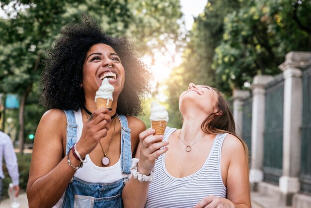 Belle donne che mangiano un gelato in strada. Concetto di gioventù.