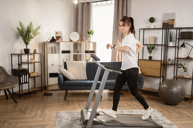 Belle donne con lunghi capelli neri e legati in leggings sportivi e maglietta bianca e scarpe da ginnastica