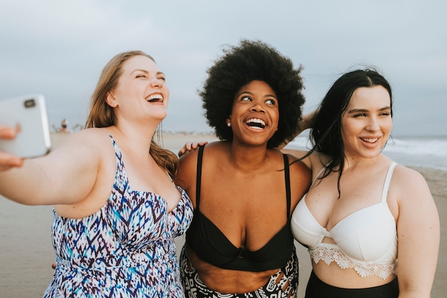 Belle donne curvy prendendo un selfie in spiaggia