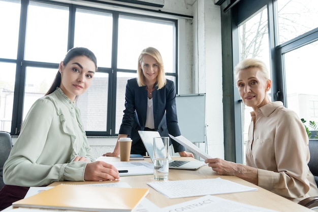 belle donne d'affari che guardano la telecamera in una riunione in ufficio