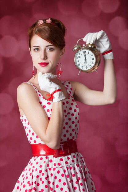 Belle donne rosse con l'orologio. Foto in stile retrò con bokeh sullo sfondo.