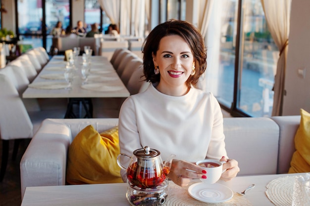 Belle donne sorridenti che bevono tè al caffè accogliente. Le donne d'affari fanno una pausa con una tazza da tè. Foto di stile di vita luminoso in un elegante caffè.