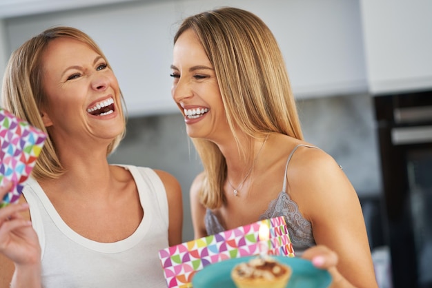 Belle due ragazze adulte in casa con la torta di compleanno