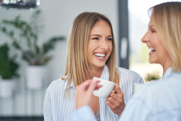 Belle due ragazze adulte in cucina con il caffè