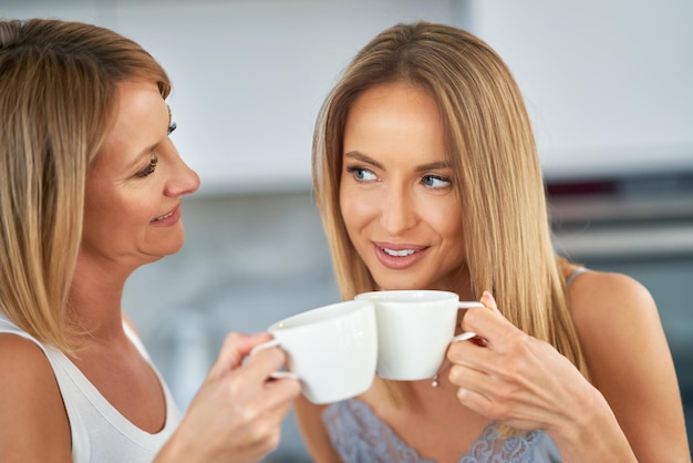 Belle due ragazze adulte in cucina con il caffè