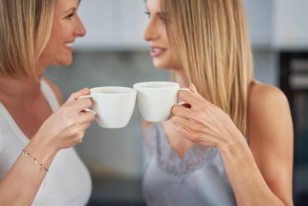 Belle due ragazze adulte in cucina con il caffè