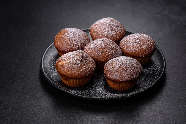 Belle e deliziose tortine con cacao e uvetta su uno sfondo di cemento nero Tempo per bere il tè