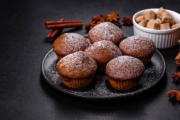 Belle e deliziose tortine con cacao e uvetta su uno sfondo di cemento nero Tempo per bere il tè